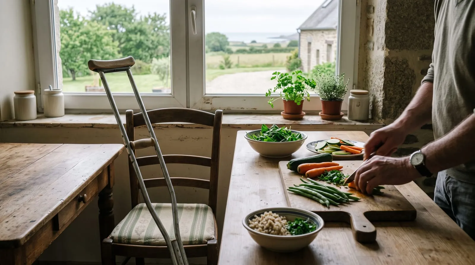 Une paire de béquilles appuyée contre une chaise de cuisine, à côté d'un plan de travail où un repas simple est en préparation.